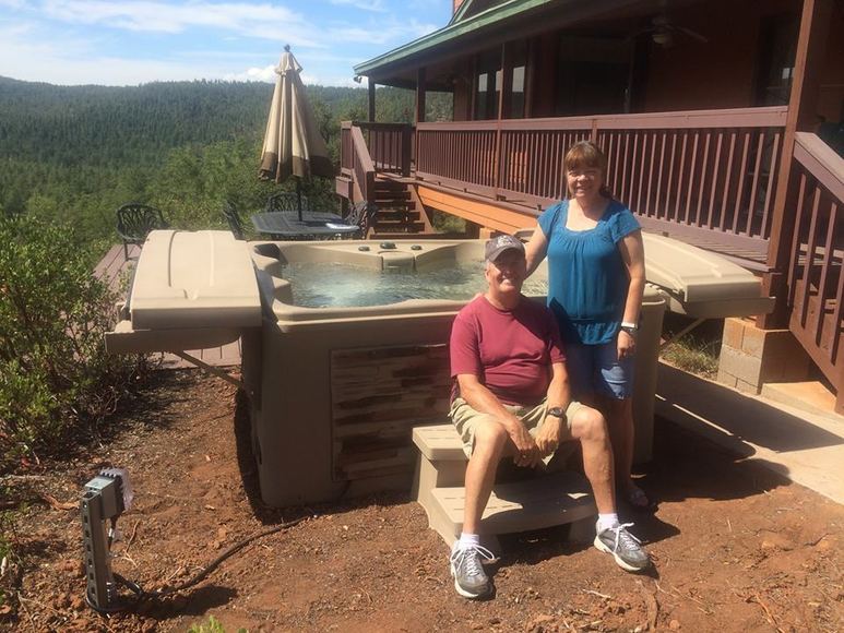 Couple beside their spa on a covered patio